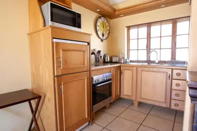 a kitchen with wooden cabinets and a microwave and a clock at Crimson Cottage in Dullstroom