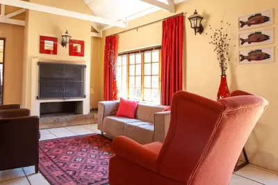 a living room with a couch and a tv at Crimson Cottage in Dullstroom