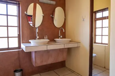 a bathroom with two sinks and two mirrors at Crimson Cottage in Dullstroom