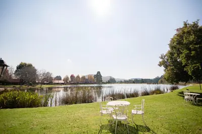 a table and chairs on the grass next to a lake at Critchley Hackle in Dullstroom