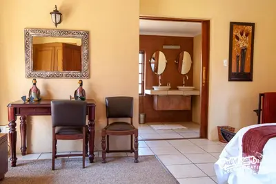 a bedroom with a bed and a desk and chairs at Critchley Hackle in Dullstroom