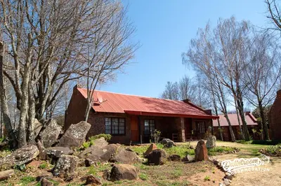 a house with a red roof and some rocks at Critchley Hackle in Dullstroom