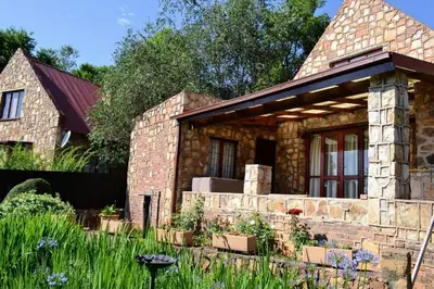 a stone house with a garden in front of it at Critchley Common in Dullstroom