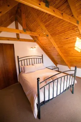 a bed in a room with a wooden ceiling at Critchley Common in Dullstroom