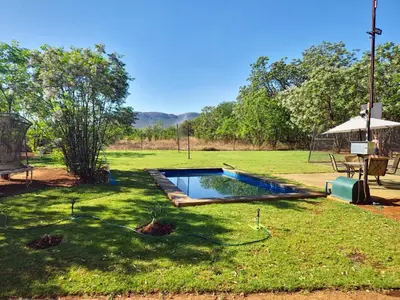 a pool in a yard with a table and an umbrella at Vulture's View 5 in Hartbeespoort
