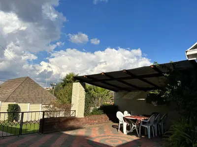 a patio with a table and chairs under a pergola at The Valley, tranquil 3 bedroom home with pool in Midrand