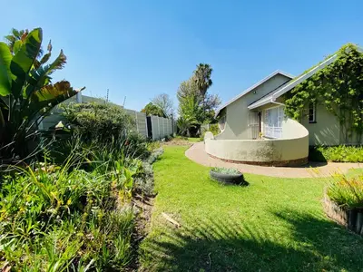 a backyard with a house and a yard with plants at The Valley, tranquil 3 bedroom home with pool in Midrand