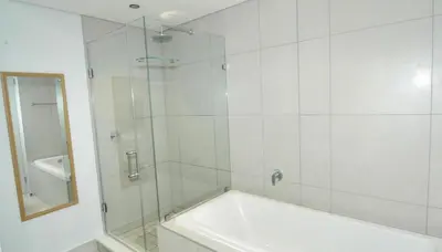 a bathroom with a tub and a glass shower at Waterfall Luxury Apartment in Midrand