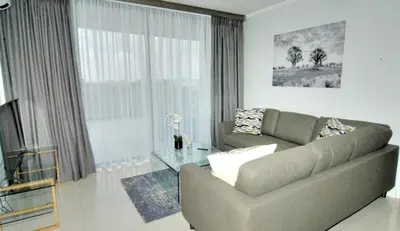 a living room with a couch and a glass table at Waterfall Luxury Apartment in Midrand