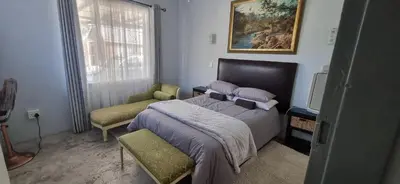 a bedroom with a bed and a chair and a window at 7-on-Burger in Polokwane