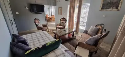 a living room with couches and chairs and a tv at 7-on-Burger in Polokwane