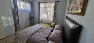 a bedroom with a bed with a couch and a window at 7-on-Burger in Polokwane