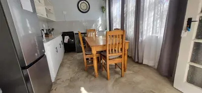 a kitchen with a table and chairs and a refrigerator at 7-on-Burger in Polokwane