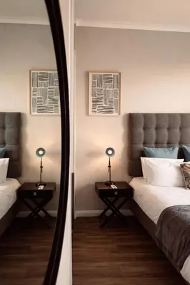 a mirror reflecting a bedroom with a bed and two tables at Menlyn Apartment - Sapphire Gold in Pretoria