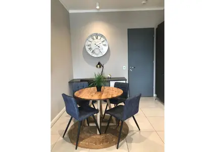 a table and chairs in a room with a clock on the wall at Menlyn Apartment - Sapphire Gold in Pretoria
