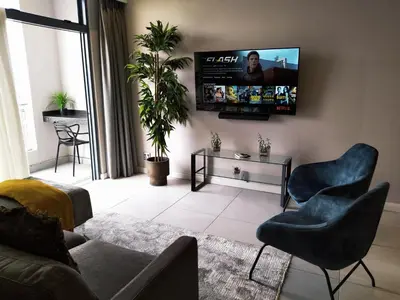 a living room with a couch and chairs and a flat screen tv at Menlyn Apartment - Sapphire Gold in Pretoria