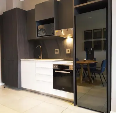 a kitchen with white cabinets and a stove and a table at Menlyn Apartment - Sapphire Gold in Pretoria