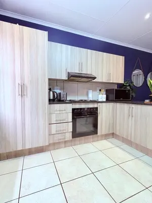 a large kitchen with wooden cabinets and a tile floor at 43 Home self Catering with backup power and High speed WiFi in Witbank