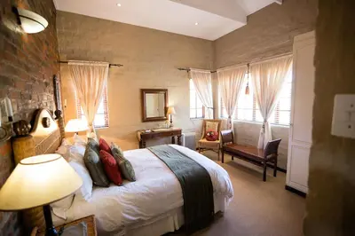a bedroom with a bed in a room with windows at Downstream in Dullstroom