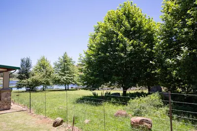 a fence in a field with trees and rocks at Downstream in Dullstroom