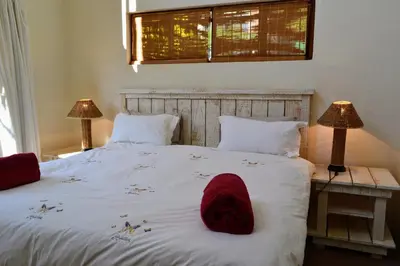 a bedroom with a white bed with a red hat on it at Upstream in Dullstroom