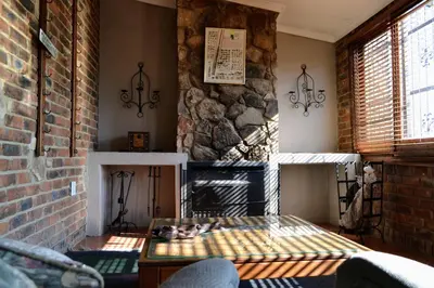 a living room with a fireplace and a brick wall at Upstream in Dullstroom
