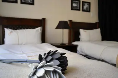 a hotel room with two beds with white sheets at Upstream in Dullstroom