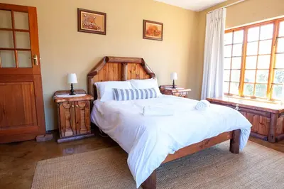 a bedroom with a large bed and two windows at Gecko Castle in Dullstroom