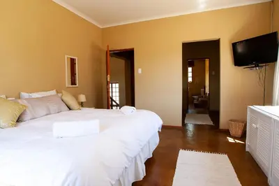 a bedroom with two beds and a flat screen tv at Gecko Castle in Dullstroom