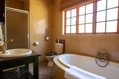 a bathroom with a tub and a toilet and a sink at Gecko Castle in Dullstroom