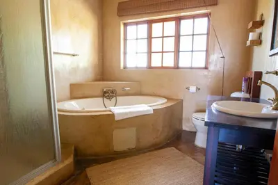 a bathroom with a tub and a toilet and a sink at Gecko Castle in Dullstroom