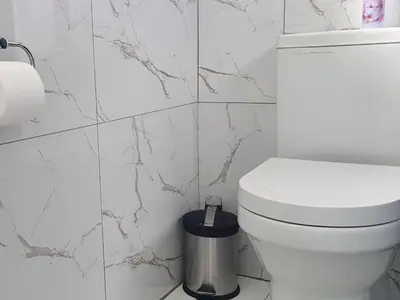 a white bathroom with a toilet and a trash can at SEA WATER BOUTIQUE LODGE in Mankweng unit G in Polokwane