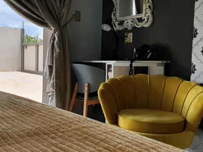 a bedroom with a yellow chair and a bed at SEA WATER BOUTIQUE LODGE in Mankweng unit G in Polokwane