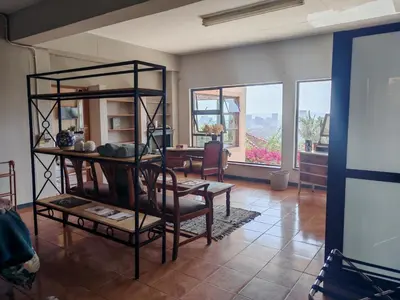 a living room with a table and chairs and windows at House Olive in Pretoria