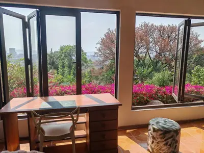 a room with a desk and windows with pink flowers at House Olive in Pretoria