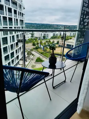 two chairs and a table on a balcony with a view at Waterfall Views From The Six- Luxurious Apartment in Midrand