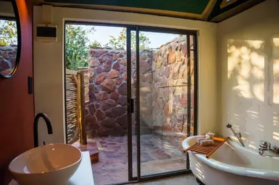 a bathroom with a tub and a toilet and a sink at Elephants Crossing in Welgevonden Game Reserve