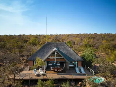 a house with a thatched roof and a deck at Elephants Crossing in Welgevonden Game Reserve