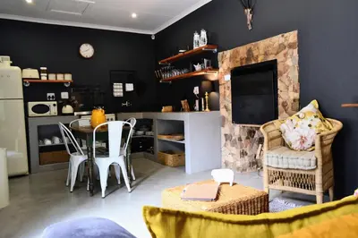 a living room with a fireplace and a table and chairs at Salt on Dullstroom in Dullstroom