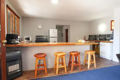 a kitchen with three bar stools and a counter at Sanctuary in Dullstroom