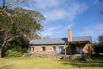 an old brick house with a chimney on a lawn at Waterval in Dullstroom