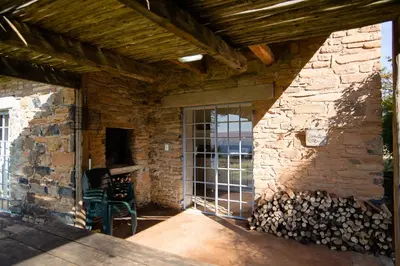 a stone building with a large window and a stone wall at Waterval in Dullstroom