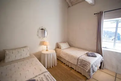 a bedroom with two beds and a table with a lamp at Waterval in Dullstroom