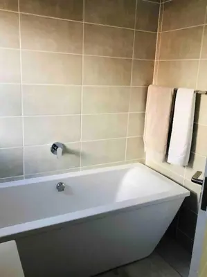 a white bath tub in a bathroom with towels at THE BLYDE LAGOON BEACH PRETORIA 3 BEDROOM GROUND FLOOR APARTMENT in Pretoria