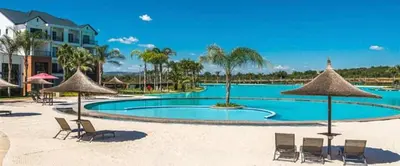 a large swimming pool with chairs and umbrellas at THE BLYDE LAGOON BEACH PRETORIA 3 BEDROOM GROUND FLOOR APARTMENT in Pretoria
