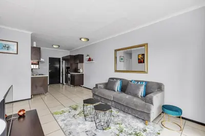 a living room with a couch and a kitchen at Smartz Apartment 76 in Midrand