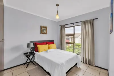 a white bedroom with a bed and a window at Smartz Apartment 76 in Midrand