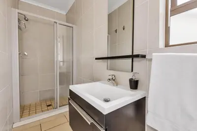 a white bathroom with a sink and a shower at Smartz Apartment 76 in Midrand