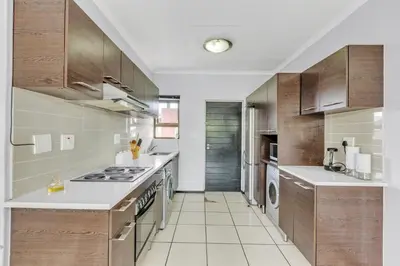 a large kitchen with wooden cabinets and white appliances at Smartz Apartment 76 in Midrand