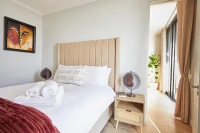 a bedroom with a white bed with a wooden headboard at Aburi at Ellipse Waterfall in Midrand